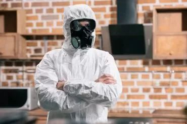 pest control worker standing in uniform with crossed arms in kitchen