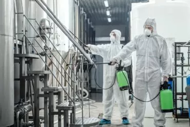 sanitation at factory of craft beer guys in protective suits disinfect at plant